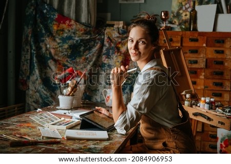 Professional young woman female artist working at her cozy workshop