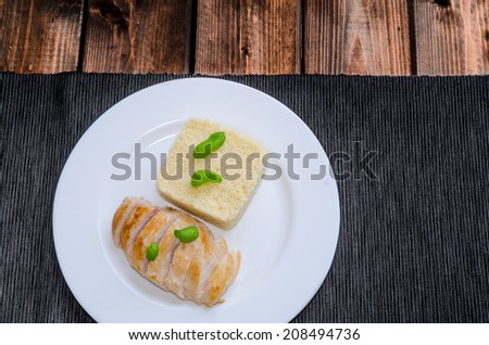 Grilled chicken breast with couscous and basil on wood table