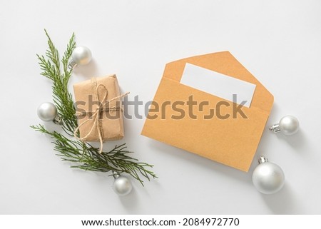 Composition with envelope, card, Christmas gift and decorations on white background