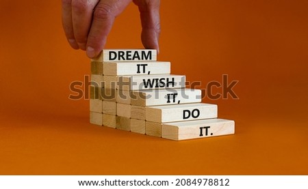 Dream wish and do it symbol. Wooden blocks with words Dream it, wish it, do it. Businessman hand. Beautiful orange background, copy space. Business and dream, wish and do bigger concept. Royalty-Free Stock Photo #2084978812