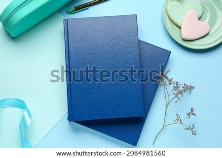 Blank books, cookies and ribbon on color background