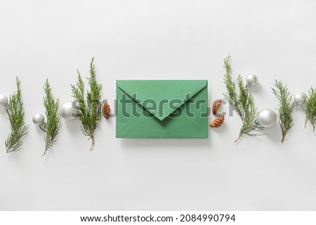 Composition with envelope, coniferous branches and Christmas decorations on white background