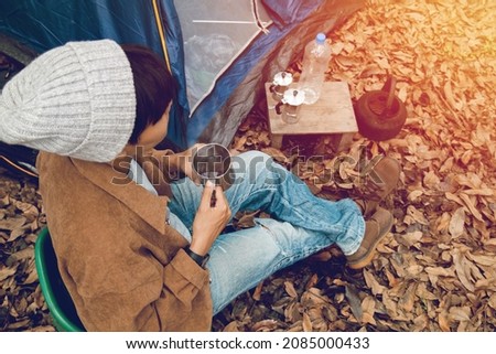 back of Asian backpacker sitting wooden, drinking brewed hot coffee using Moka pot coffee outside the tent vacation in holiday trip in the forest lifestyle alone camping in the morning winter season