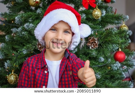 Happy boy in santa claus hat on the background of the christmas tree. Christmas and New Year concept