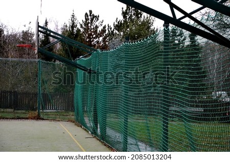 multifunctional outdoor playground for ball games at school. green artificial turf from a plastic carpet with lines. basketball hoops and soccer goals. around the grabbing high net and guardrails 