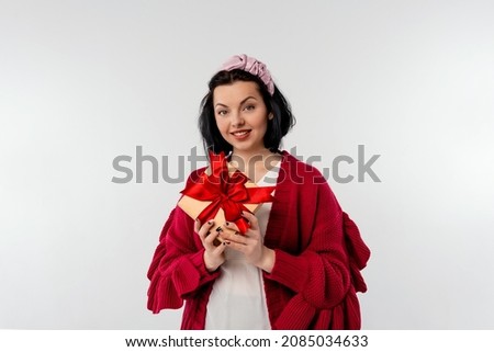beautiful young woman holding valentine gift box and looking at camera with a happy smile on face, standing over white background. New Year Women's Day birthday holiday concept