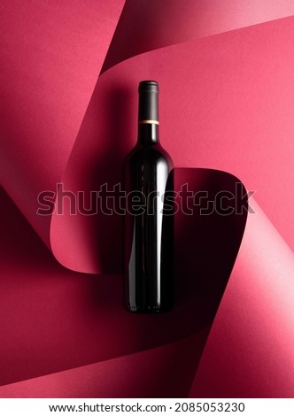 Bottle of red wine on a red background. Top view.