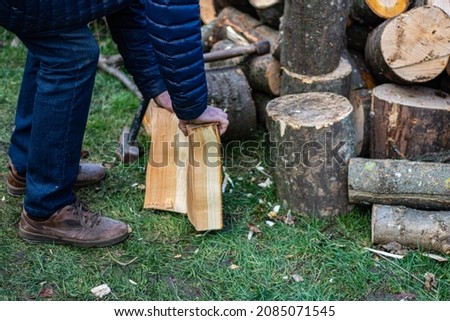 Man chopping wood with an ax in his hand. Standing by a log for chopping wood.