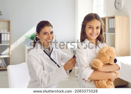 Portrait of smiling caring young female pediatrician listen lungs do checkup for little girl child. Happy woman doctor or GP examine small teen kid at consultation in hospital. Healthcare concept. Royalty-Free Stock Photo #2085075028