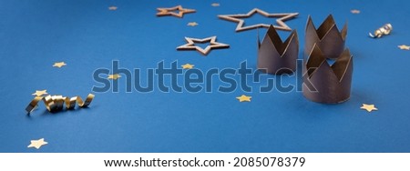 Traditional Three King's Day of January 6. Three gold crowns on blue background with winter decorations. Happy Epiphany day, copy space.