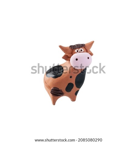 Clay cow figurine on white background, isolated object. A toy.