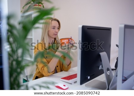 young woman sits at a computer in the office. remote work concept.
