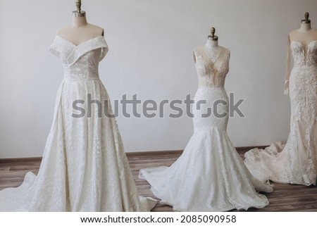 There are three pretty white dresses. They are really long. Each dress has its own interesting ornament.