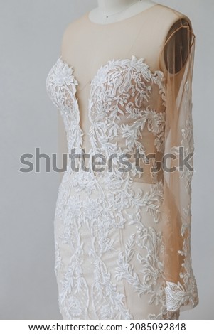 There is unfinished dress on the white background. The dress already has a beautiful ornament.