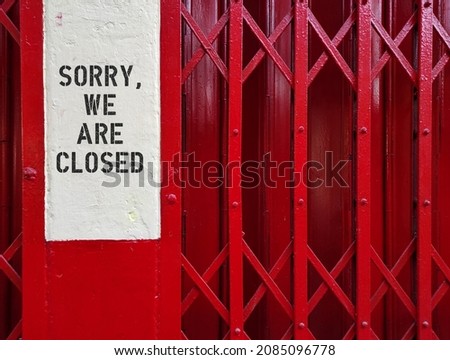Red Asian commercial shop house stretch door with text written SORRY WE ARE CLOSED, concept of sign to inform visitor or customer the place,shop or building are closed, temporaly or permanent