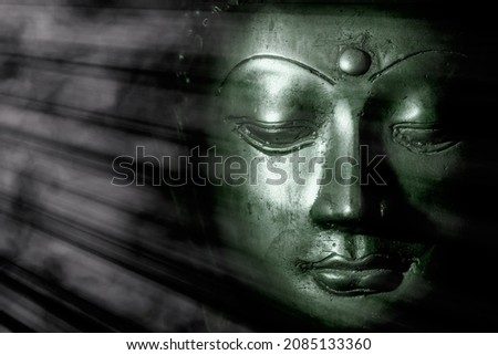 Zen buddhism and spiritual enlightenment. Mindful green toned buddha face illuminated by mystical heavenly light. Peaceful esoteric expression of contemplation relating to meditation and the Universe