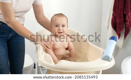 Happy smiling baby boy enjoying having bath. Concept of children hygiene, healthcare and parenting.