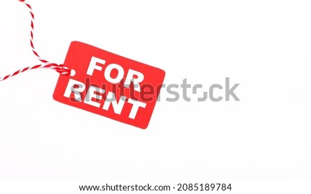 The inscription FOR RENT on a red price tag on a light background. Advertising concept. Copy space