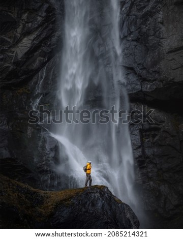 
Backpacker man in yellow jacket explores waterfall in Switzerland Royalty-Free Stock Photo #2085214321