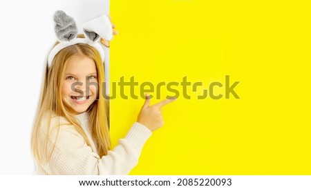 girl with bunny ears smiling and looking on yellow background, easter, banner