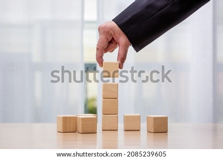 Businessman arrange wooden blocks stacked in uneven steps like obstacles, business growth journey success concept. copy space.