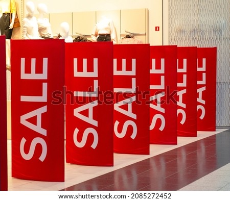 Sale in the store. Red posters with the inscription SALE at the entrance to the clothing department