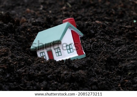 The toy house fell into the mud. Concept for real estate, mortgage, earthquake Royalty-Free Stock Photo #2085273211