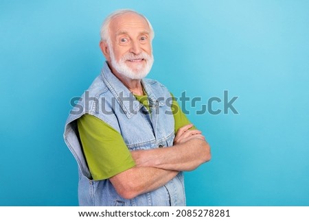 Photo of handsome cute retired man wear vintage jeans waistcoat smiling arms folded empty space isolated blue color background
