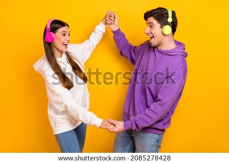 Photo of two crazy millennial people hold arms enjoy sound chilling free time isolated on yellow color background