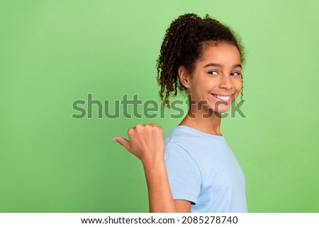 Portrait of attractive cheerful girl demonstrating copy space ad advert isolated over green pastel color background