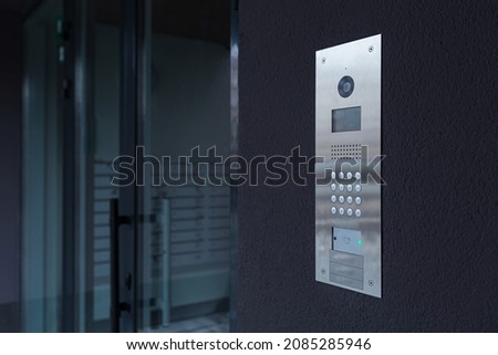 Entrance doorbell in a multi-apartment building, with a video surveillance camera, on a dark wall Royalty-Free Stock Photo #2085285946