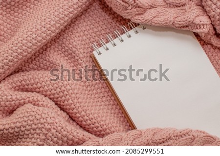 a spring-loaded notebook on a pink knitted plaid Royalty-Free Stock Photo #2085299551