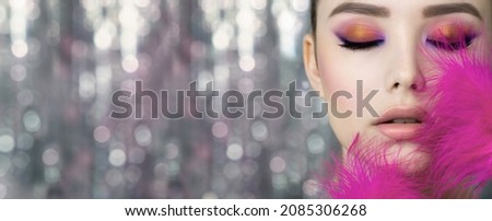 Portrait of beauty model with bright color makeup. Face of beautiful young woman with professional make up  and vivd pink feathers. Close up, selective focus. Royalty-Free Stock Photo #2085306268