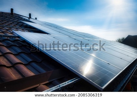Solar panel on a red roof reflecting the sun and the cloudless blue sky Royalty-Free Stock Photo #2085306319