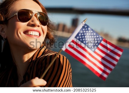 Woman waving American flag by urban bridge