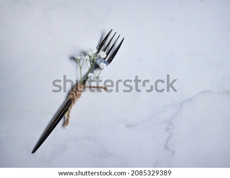 fork, gypsophila flower on concrete background