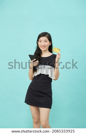 Beautiful Asian woman use smartphone and credit card payments online shopping online on light blue studio isolated background
