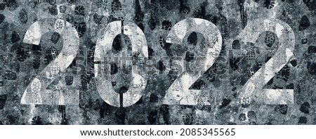 2022 numbers on asphalt covered with footprints on the melted snow in bad weather in winter. The concept of an unhappy year