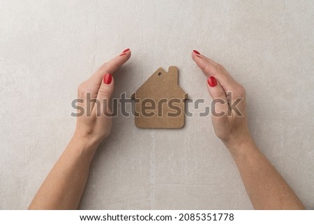 concept of protection and love for the home. flat model of a wooden house with female hands