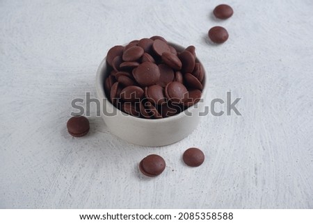 choco chips or chocolate morsels in white bowl on texture white background.isolated