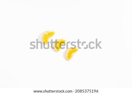 Three small slices of tangerine lie diagonally on a white background. View from above. Flat lay. Isolate. Life style. Clos up. Horizontal photo.