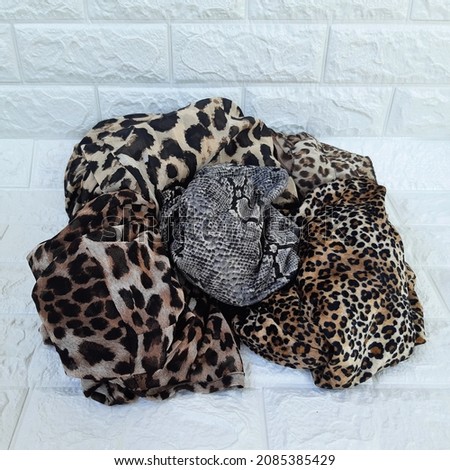 A collection of scarves with various animal print motifs on a white background