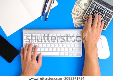 Man hands working on modern laptop. Office desktop on blue background, caculator and notebook on blue colour background. Business, Insurance or money concept