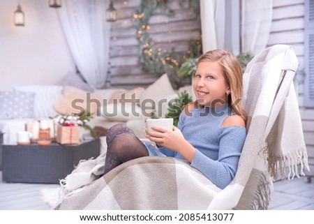 Beautiful blonde girl on the Christmas porch. Drinking tea.