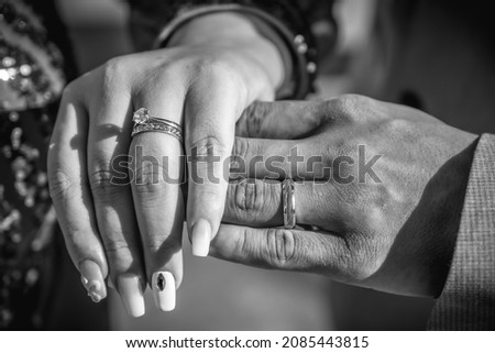 Hand of newlyweds with the rings just put on after the wedding, black and white photography