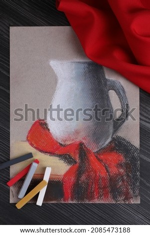 Colorful chalk pastels and beautiful painting of jug on black wooden table, flat lay