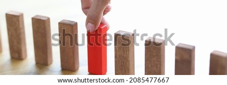 Man hand choosing red block among wooden closeup. How to make right choice concept