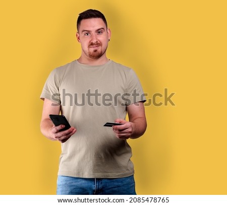 Studio photo of a man gesturing as he makes a credit card purchase with his mobile