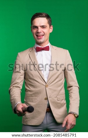 Portrait of professional male reporter holding microphone, isolated on white and green background