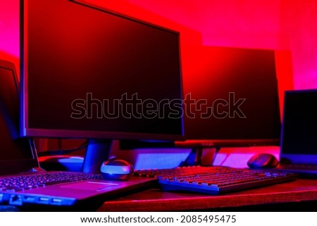 Creator's workplace in colored neon light. Computer equipment for creating visual content. Freelancer home office in pink blue light. Home office concept